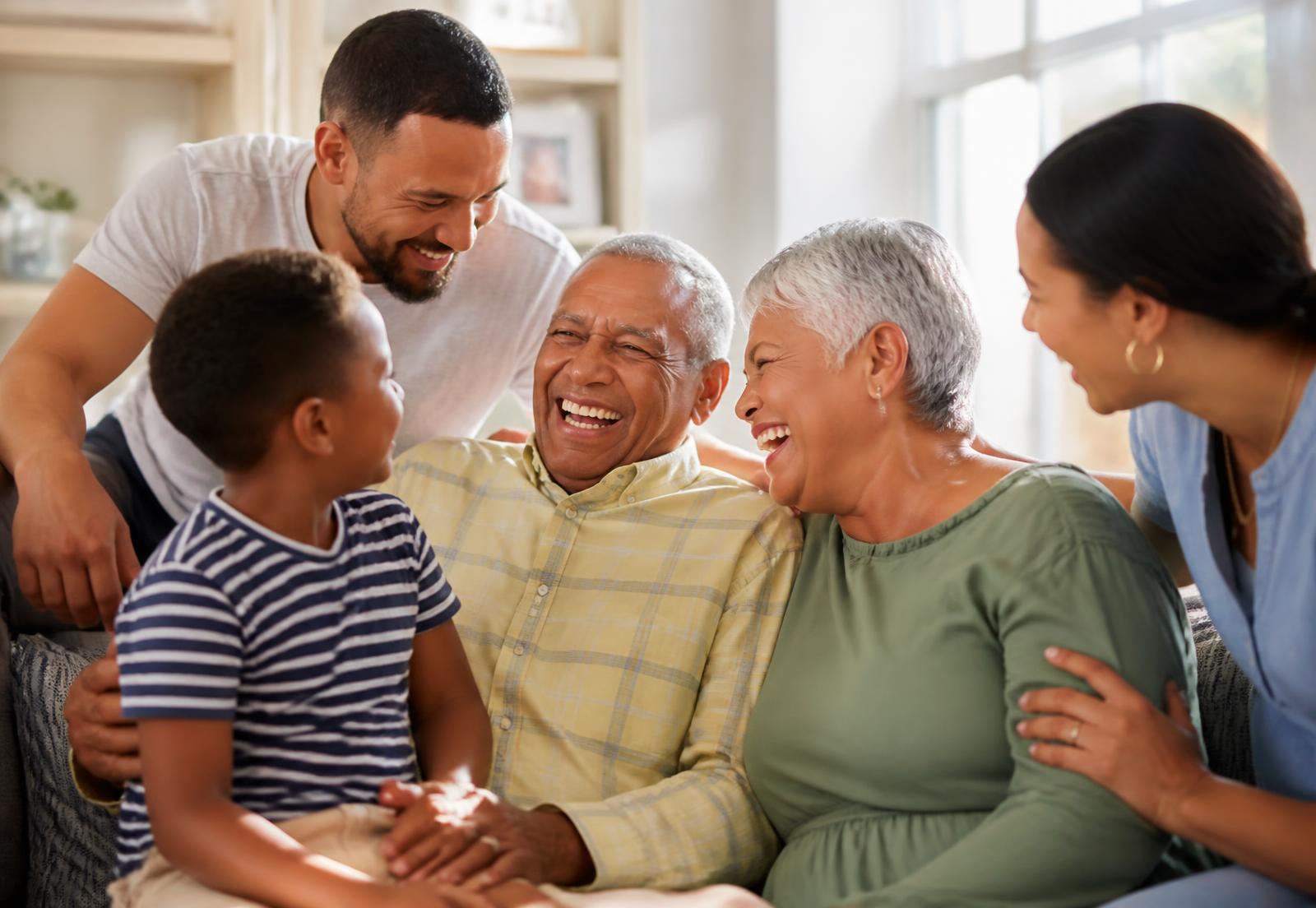 A multigenerational family laughing together with an elderly loved one at home